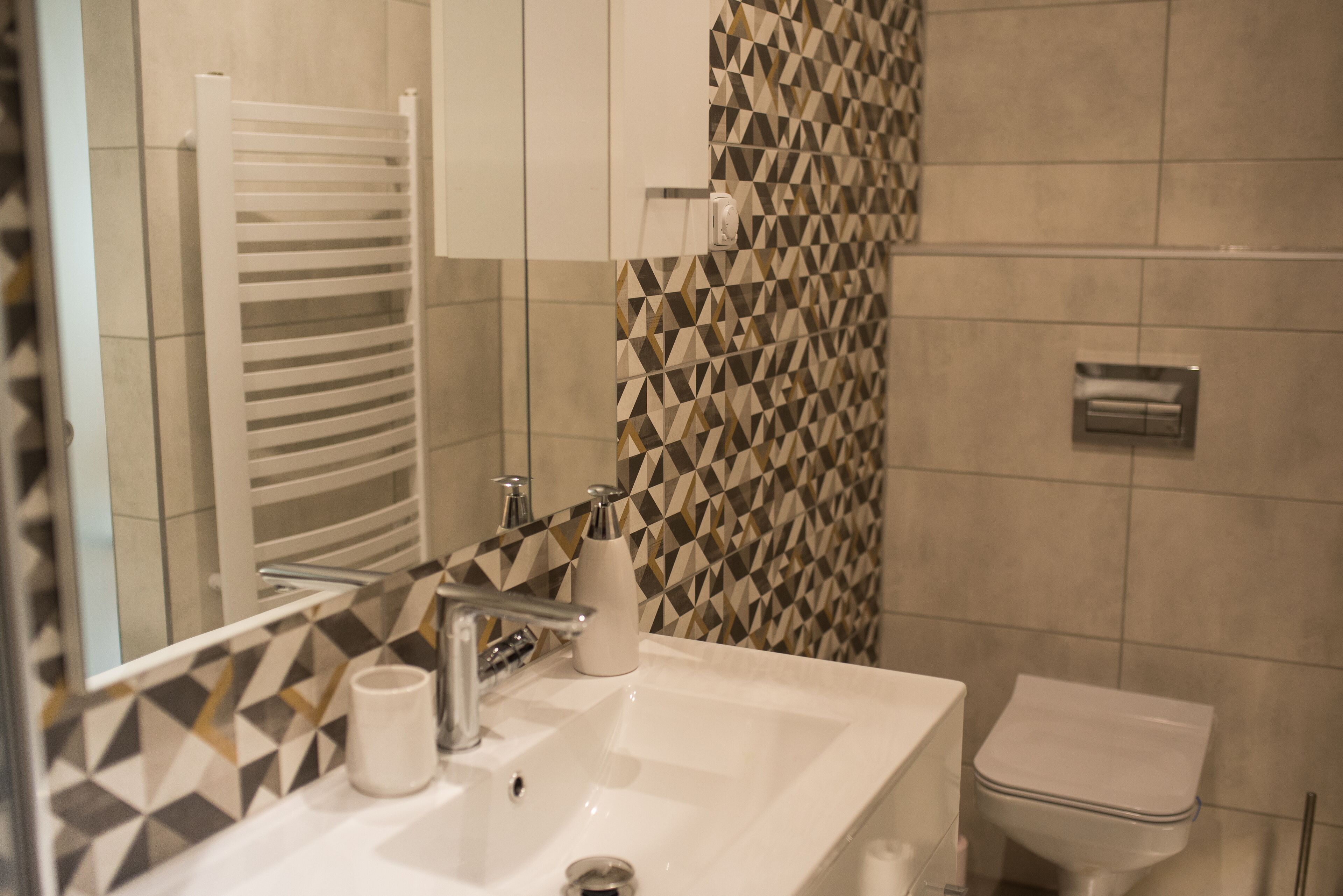 Un baño con lavamanos blanco, un espejo, toallero y un inodoro.