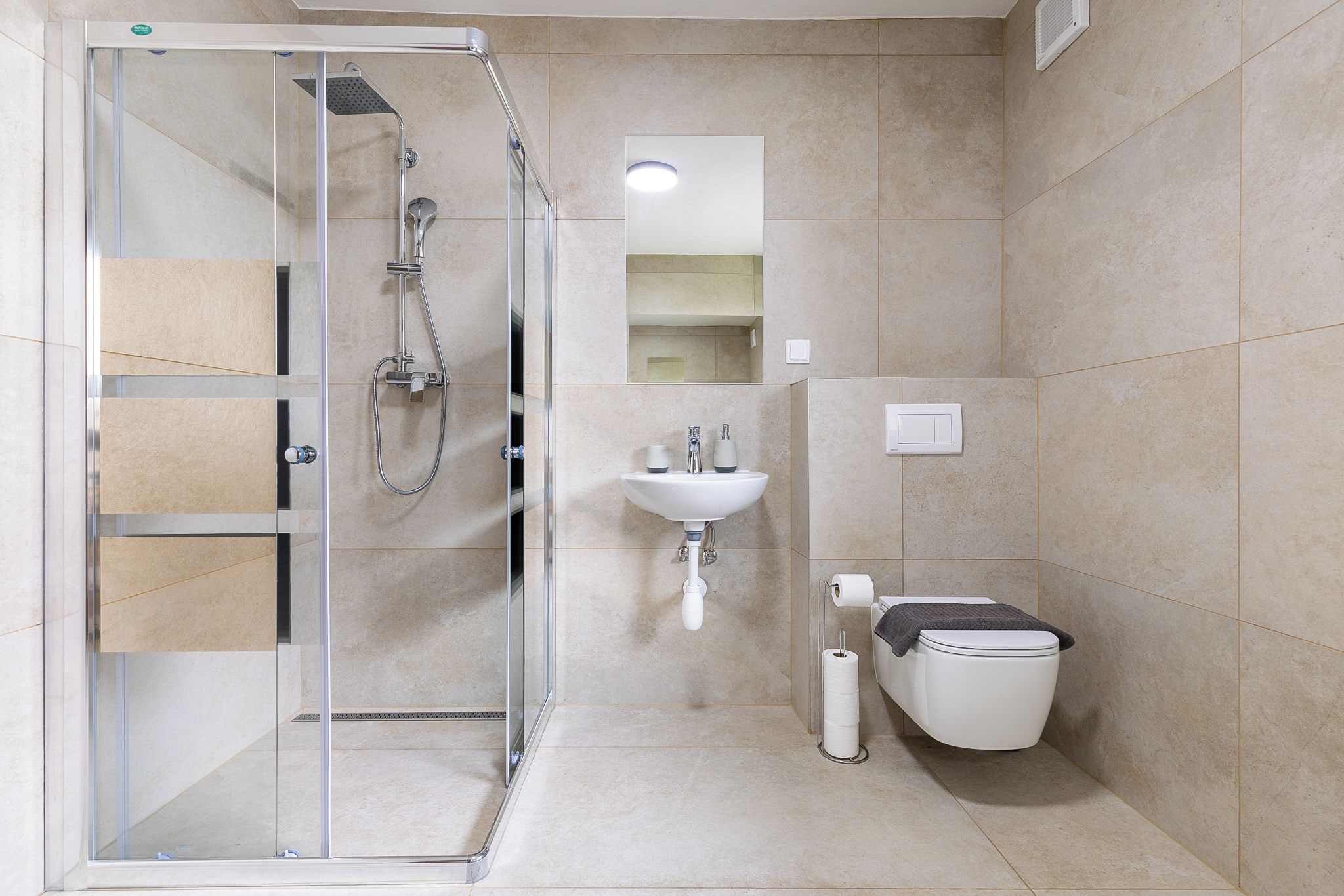 Un baño moderno con cabina de ducha de vidrio, un lavamanos y un inodoro.