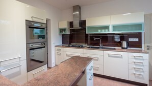 Una cocina moderna con armarios blancos, electrodomésticos de acero inoxidable y encimera de granito.