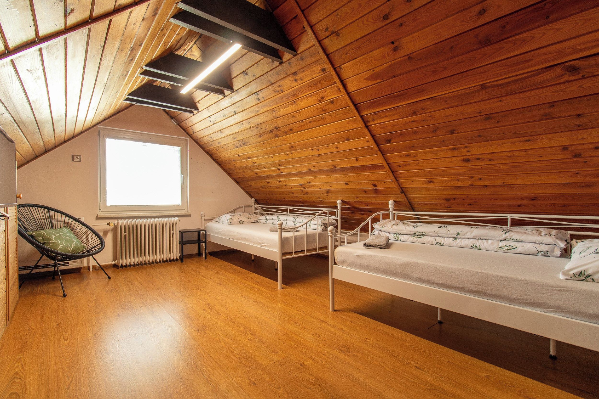 Une chambre de dortoir avec deux lits superposés, un radiateur, une chaise et une fenêtre.