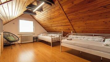 Une chambre de dortoir avec deux lits superposés, un radiateur, une chaise et une fenêtre.