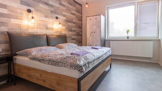 Un dormitorio moderno con cama de madera, armario y ventana con persianas.