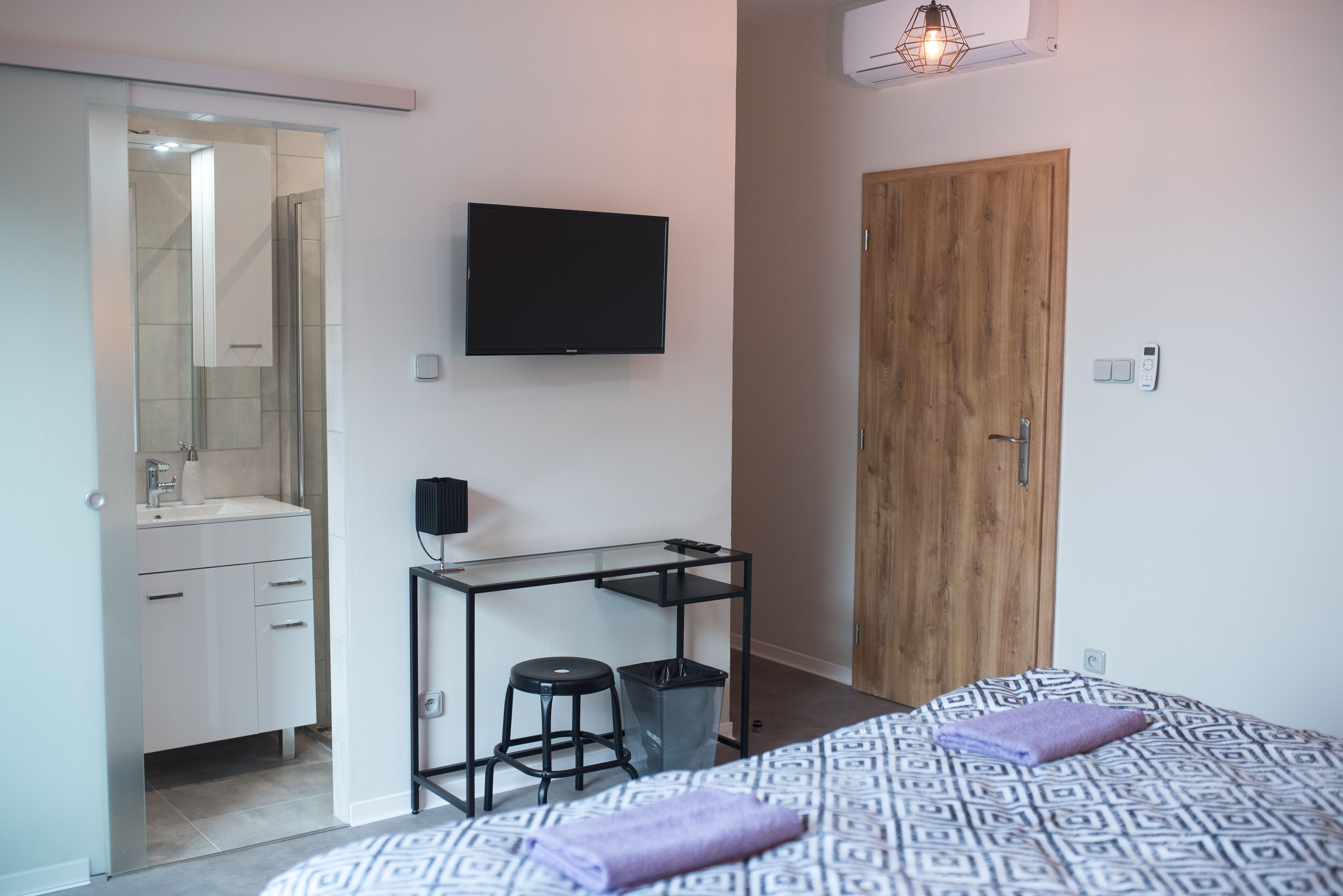 Un dormitorio con cama, escritorio, televisor, armario y baño.