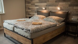 A bed with patterned bedding, a wooden frame, and two wall-mounted reading lights. - Penzion Moon (Ostrava)