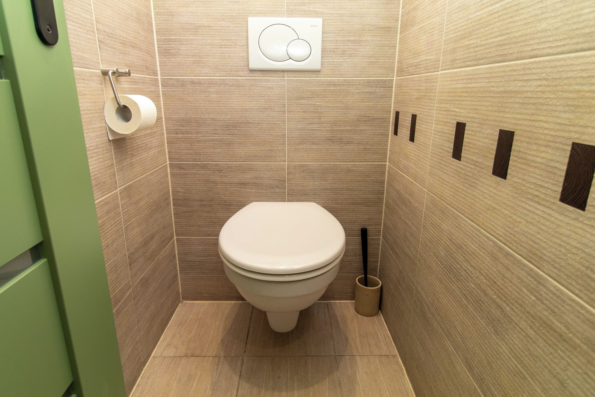 Un baño pequeño y moderno con inodoro, dispensador de papel higiénico y bidé.