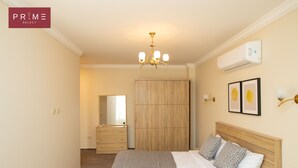 A bedroom with a bed, bedside lamps, a wardrobe, and a chandelier. - Prime Select Marvel New Cairo (New Cairo)