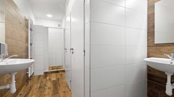 Uma casa de banho moderna com duas pias, soalho em madeira e azulejos brancos.