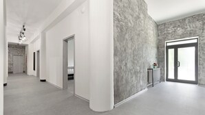 A spacious hallway with a modern design, featuring a concrete accent wall, a radiator, and a door leading to another room. - Hostel na Šalamouně (Ostrava)
