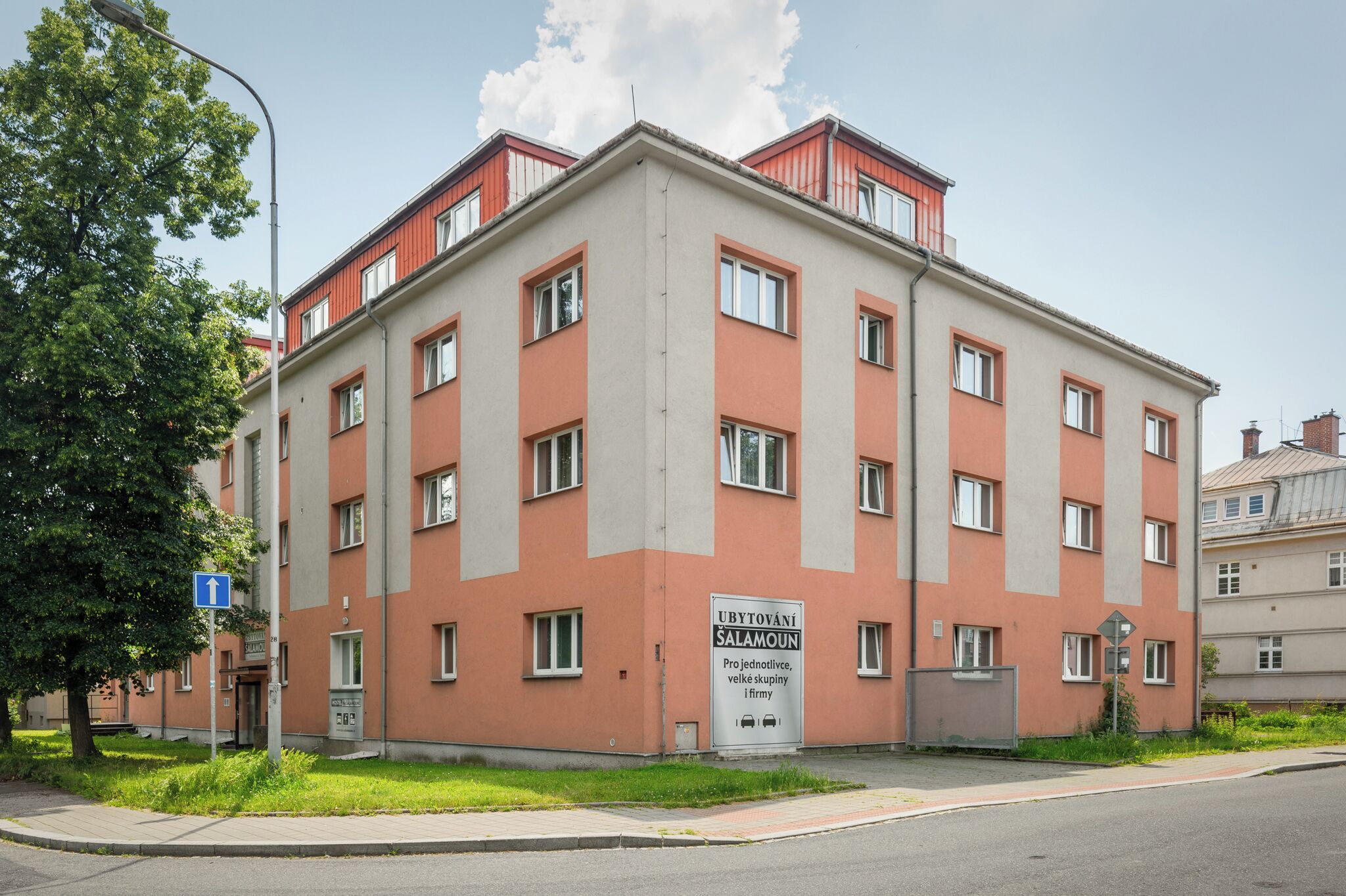 A multi-story building with a red and beige facade, featuring multiple windows and a visible entrance.