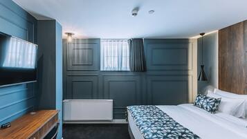 Un dormitorio con cama, televisión, radiador y ventana con cortinas.