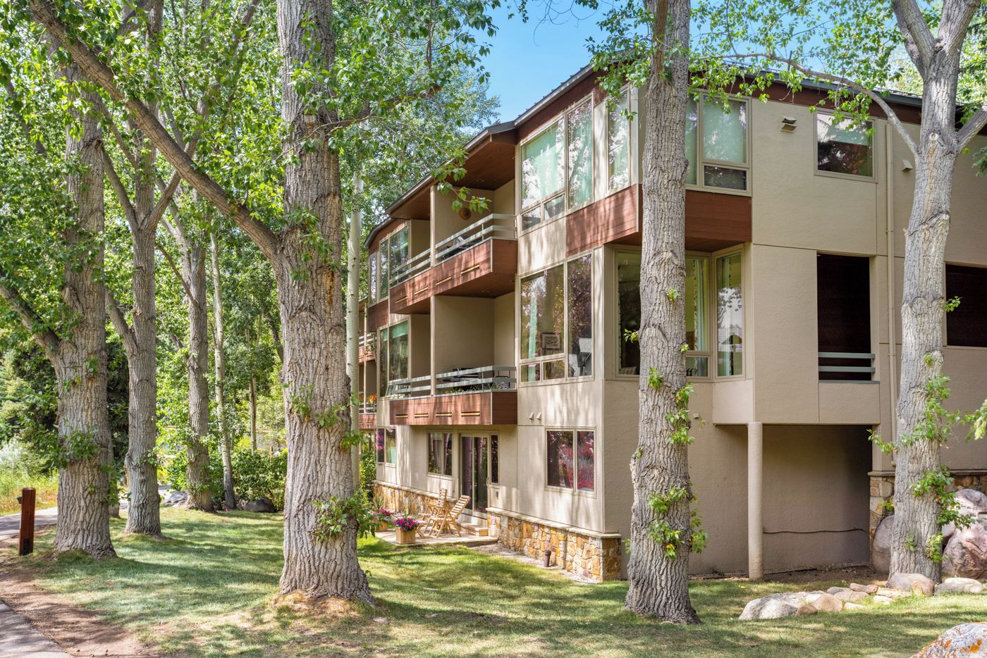 A multi-story building with balconies, surrounded by trees.