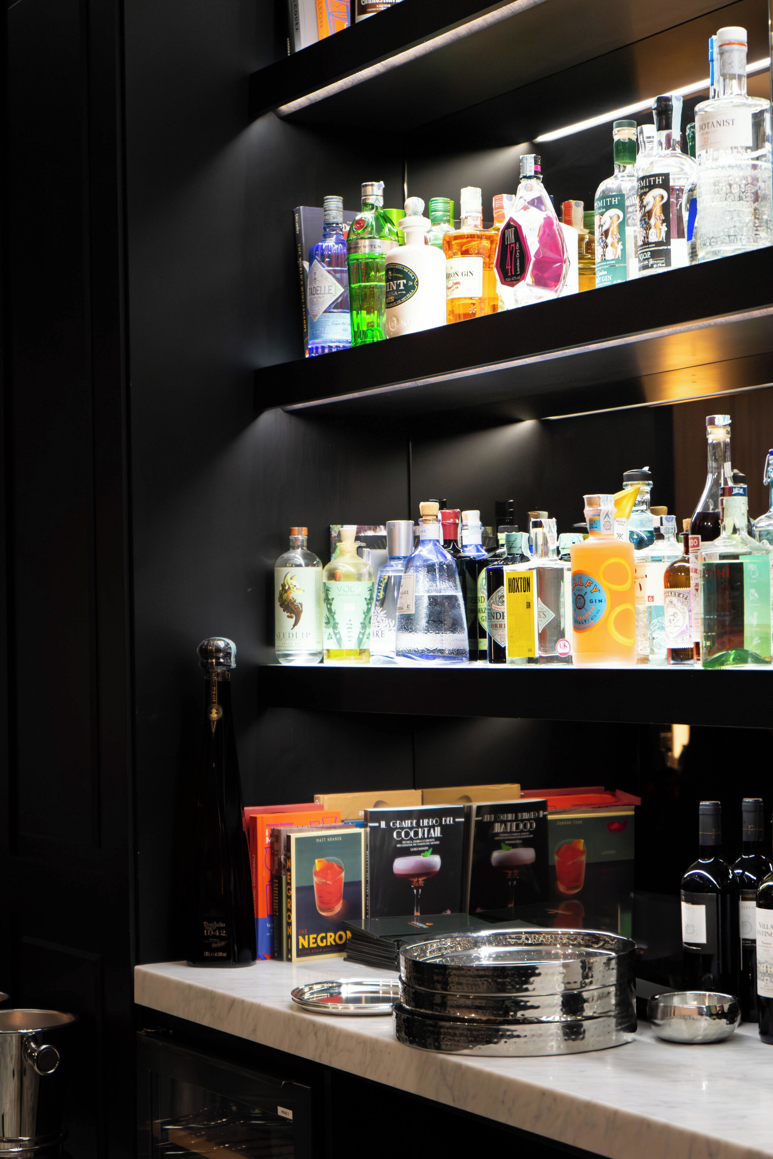 A bar area with shelves stocked with various liquor bottles and a selection of books.