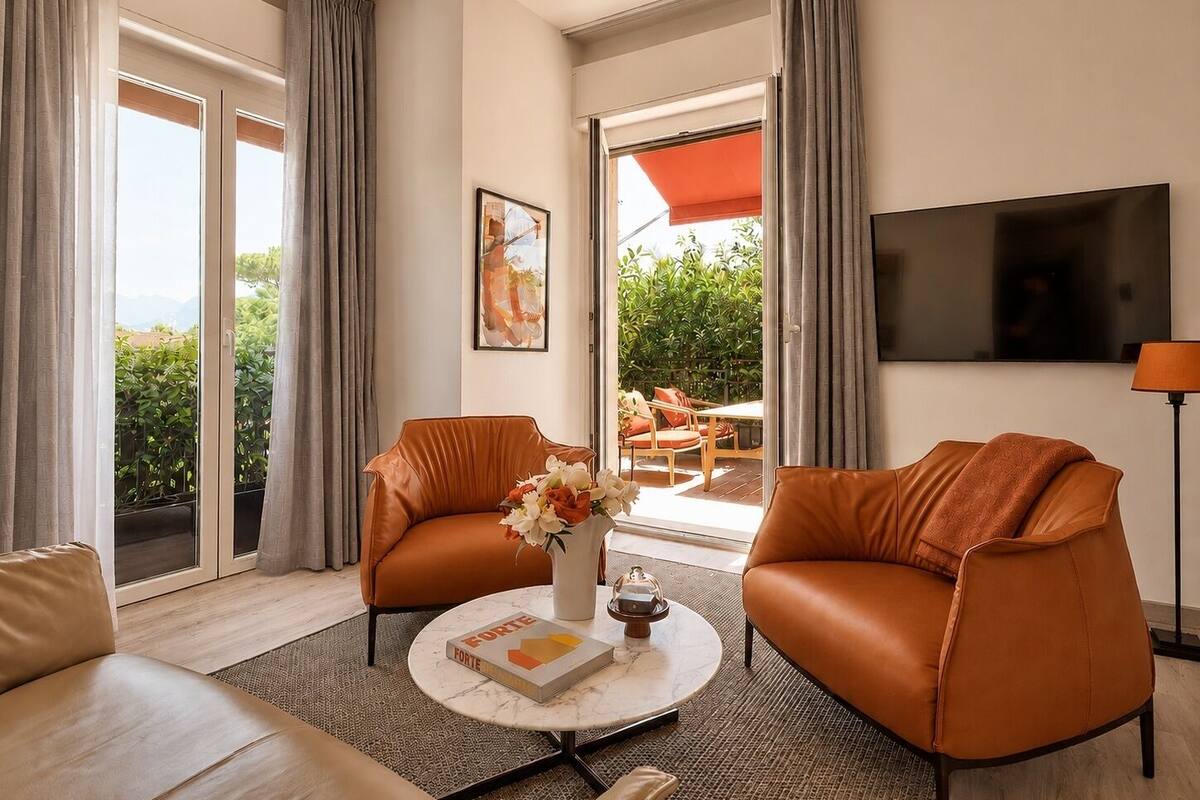 A modern living room with leather armchairs, a coffee table with a book, and a TV on the wall.
