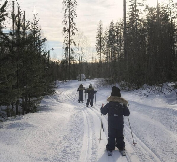Un sentier forestier enneigé, avec des skieurs.