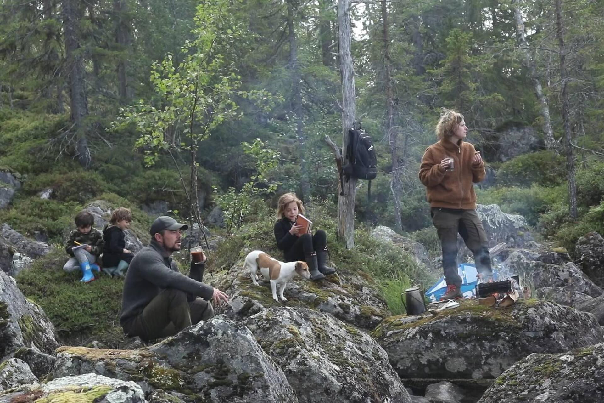 A group of people sitting on rocks in a forested area.