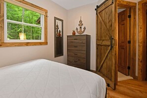 Un dormitorio con cama, cómoda, espejo y puerta de madera.
