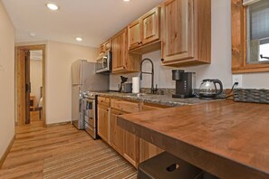 A kitchen with wooden cabinets, stainless steel appliances, and a granite countertop. - Pet Friendly - Close to Town - w/ Deck & Fire Pit (Lake George)