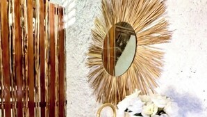A bathroom with a wooden vanity, a gold mirror, and a vase with white flowers. - zaya lençois hotel (Santo Amaro do Maranhão)