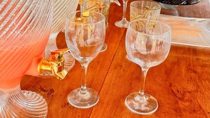 A wooden table with several clear glassware items, including a pitcher and multiple wine glasses, set up for a meal or gathering. - zaya lençois hotel (Santo Amaro do Maranhão)
