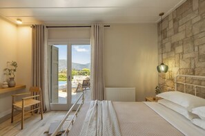 Ein Schlafzimmer mit Bett, Stuhl, Nachttisch, Lampe und Blick ins Freie.