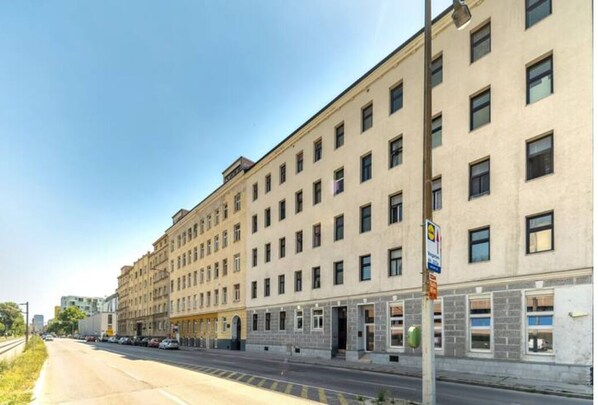 En byggnad med flera våningar och en rad fönster i bottenvåningen, troligen ett hotell eller en kontorsbyggnad.