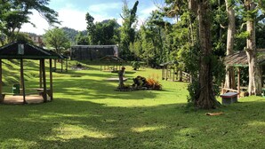 Un parque con un pabellón, mesas de picnic y un pequeño edificio.