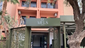 The entrance to Le Mels Hotel with a covered walkway and decorative screens. - Avenue Echouhada (Marrakech)