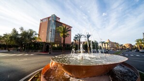 A large, circular water fountain in the middle of a street with a modern building in the background. - Avenue Echouhada (Marrakech)