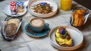 A breakfast setting with various dishes, including toast, coffee, and a croissant, on a marble table. - Avenue Echouhada (Marrakech)