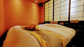 A hotel room with a bed, a window with a grid pattern, and a wall-mounted control panel.