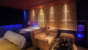 A room with a bed, a sofa, a table with bottles, and a wall with intricate carvings. - HOTEL FOURSEASON - Adults Only - (Takaoka)