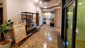A hotel lobby with a reception desk, a bookshelf with books, a potted plant, and a sign listing amenities. - HOTEL FOURSEASON - Adults Only - (Takaoka)