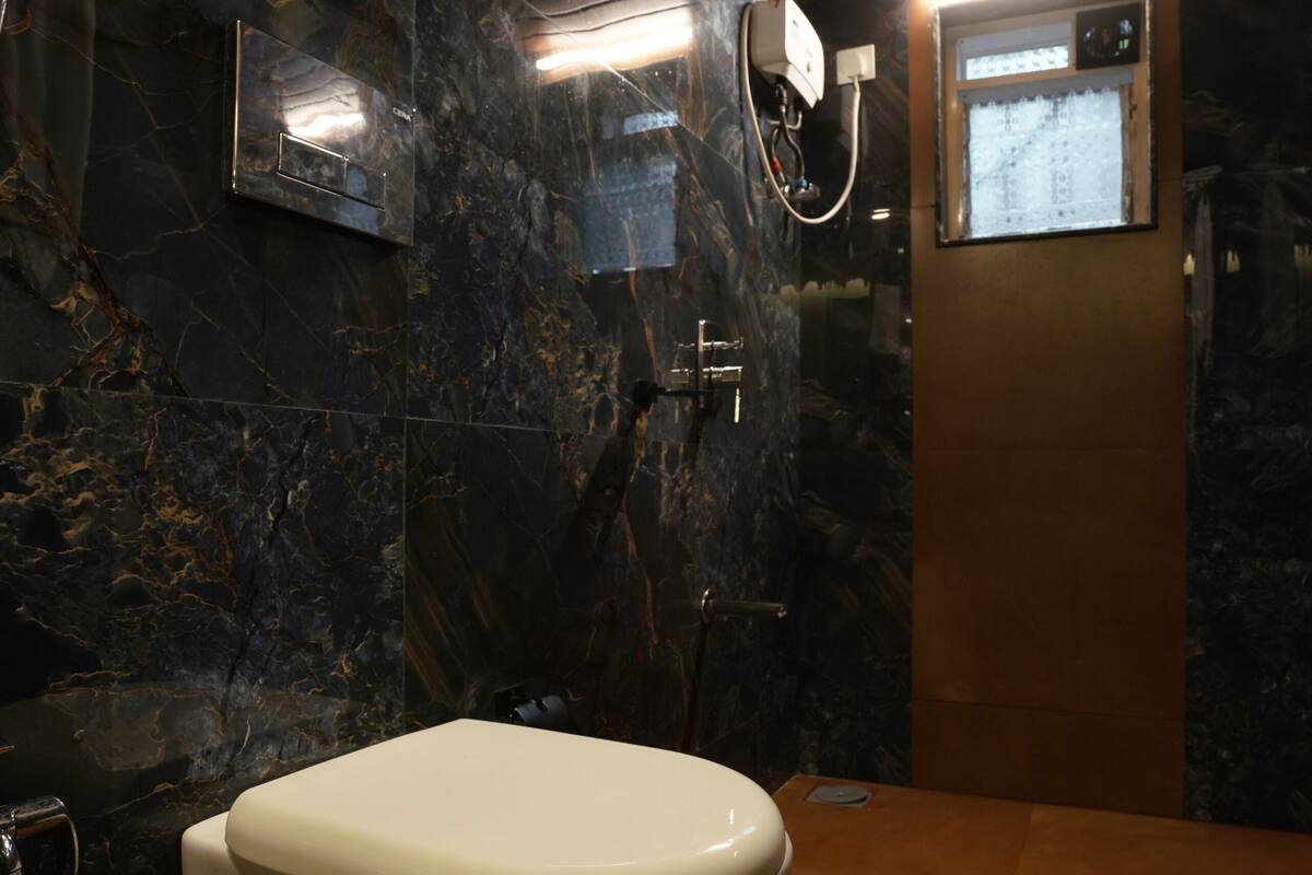 A modern bathroom with a marble wall, a wooden floor, and a white toilet.