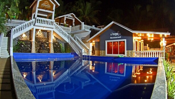 A resort with a swimming pool, a restaurant, and a staircase leading to a deck. - Siddhant Hill Resort (Murud)