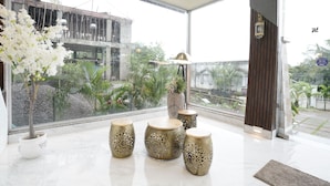 A modern interior with large windows, a potted plant, and decorative vases. - Siddhant Hill Resort (Murud)