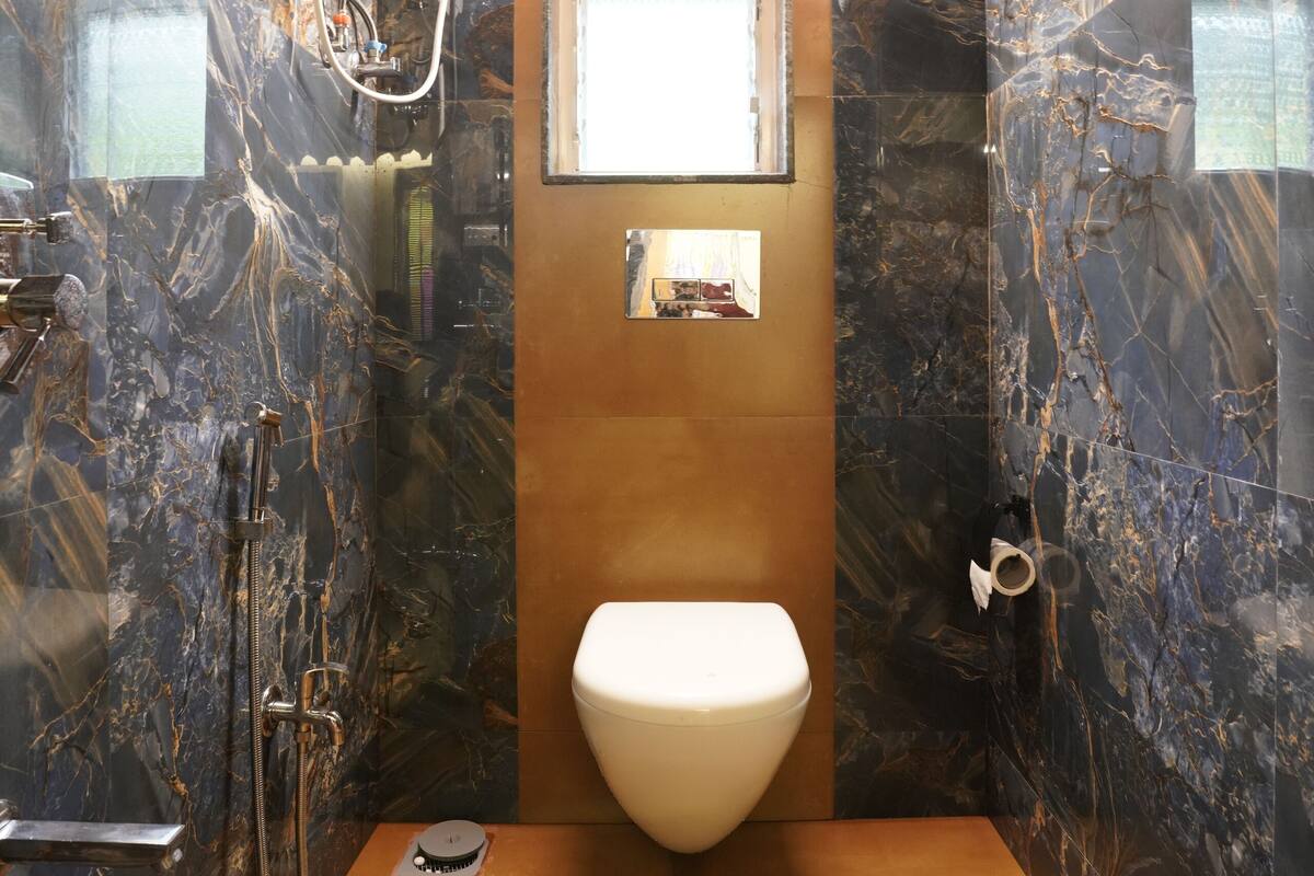 A bathroom with a marble wall, a wooden ceiling, a white toilet, a shower, and a towel rack.