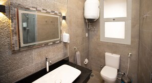 A modern bathroom with a large mirror, a sink, a toilet, and a shower.