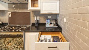 Een keuken met een fornuis, een spoelbak en een aanrecht met waterflessen en een koffiezetapparaat.