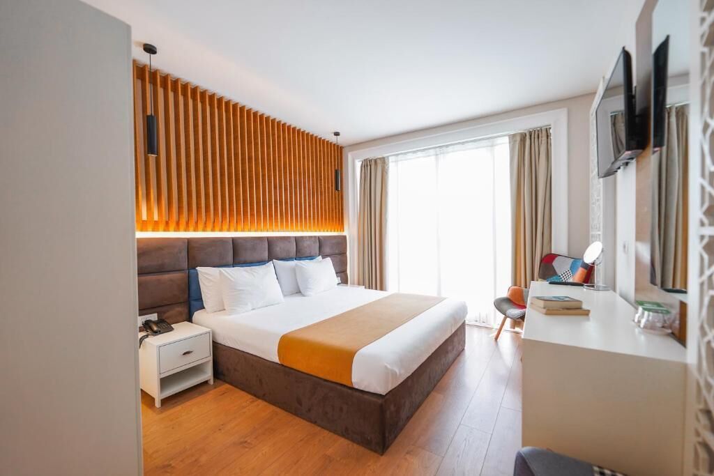 Una habitación de hotel moderna con una cama grande, un escritorio y un televisor.