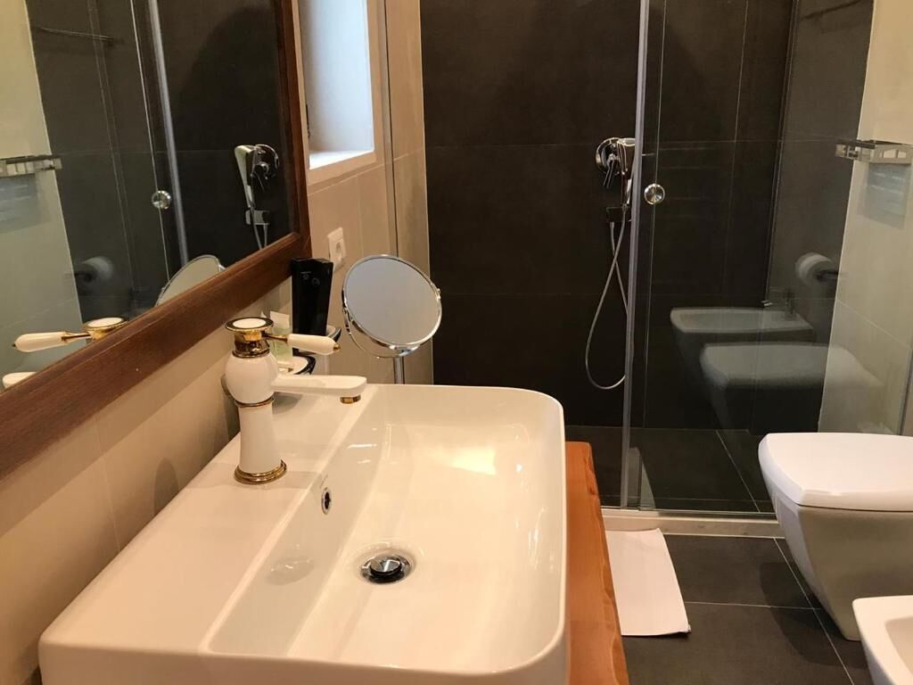 A modern bathroom with a large sink, mirror, and shower area.