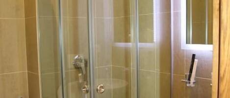 A modern bathroom with a glass-enclosed shower, a white sink, and a wooden vanity.