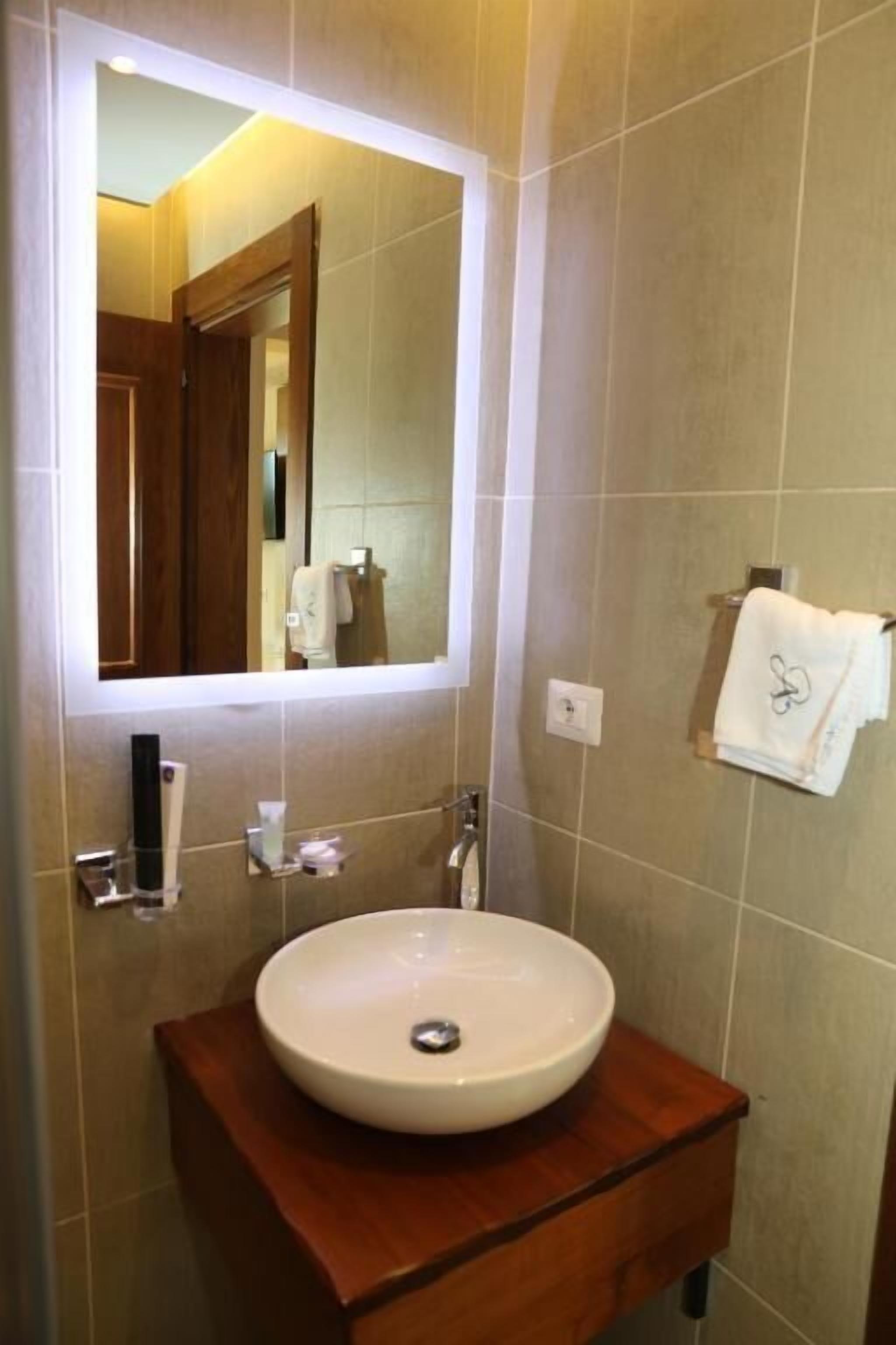 A bathroom with a round sink, a mirror, and a towel rack.
