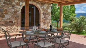 A stone building with a covered patio table set for dining, featuring a view of greenery and hills. - Fienile al Corno, Radda in Chianti, Siena and Chianti (Radda in Chianti)