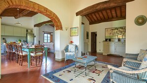 A spacious living area with a dining table set for six, surrounded by wicker furniture and a patterned rug. - Fienile al Corno, Radda in Chianti, Siena and Chianti (Radda in Chianti)