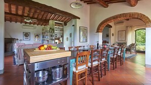 A spacious kitchen with a wooden island, a dining area with a long table, and a cozy seating area with a fireplace. - Fienile al Corno, Radda in Chianti, Siena and Chianti (Radda in Chianti)