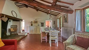 A spacious living area with a dining table set, a red sofa, and a floral-patterned armchair. - Il Pascolo, San Gimignano, Siena and Chianti (San Gimignano)
