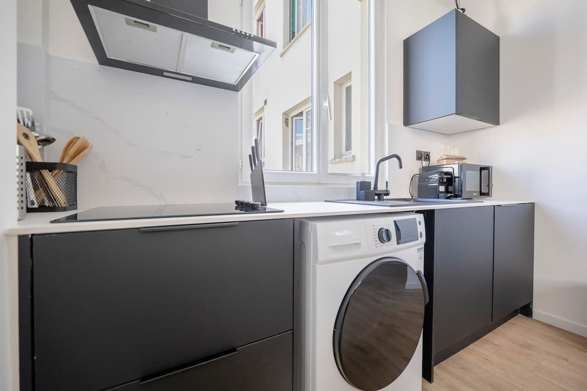 A compact kitchen with a built-in washer and dryer, a modern faucet, and a microwave.