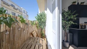 A balcony with a wooden bench, a bamboo fence, and potted plants.