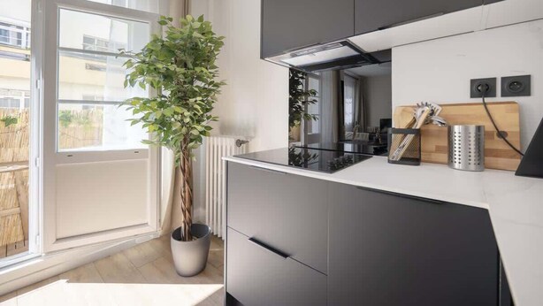 A modern kitchen with a large window, a potted plant, and a built-in oven.