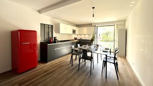 Eine moderne Küche mit einem roten Kühlschrank, Holzboden und einem Essbereich mit Tisch und Stühlen.